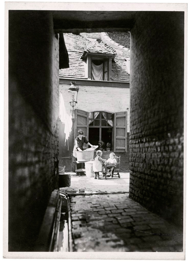 Photographie de courée, lavandière à l’ouvrage et deux enfants.